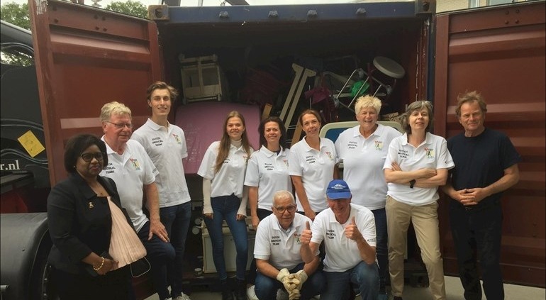Vrijwilligers bij een volle container met ziekenhuismaterialen voor Tanzania